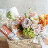 Flower and gift basket with pastel roses, hydrangeas, and snacks