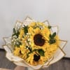 Hand-tied bouquet of bright yellow sunflowers and tiny white blooms wrapped in cream and gold paper