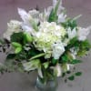 White lilies and hydrangeas arranged in a clear glass vase