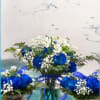 Blue and white flower arrangements in glass vases with ribbon