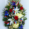 Large floral wreath with red roses, white lilies, and blue flowers