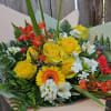 Bouquet of yellow roses, orange gerbera daisies, and white flowers wrapped in paper