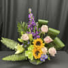 Mixed bouquet with pink roses, sunflowers, and purple flowers in a vase