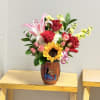 A single bold sunflower centerstage brightens this mixed bouquet, surrounded by red
