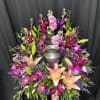 Colorful floral wreath around a silver urn on black drape