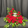 Red roses arranged around a silver urn on a black draped table