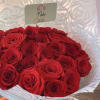 Bouquet of red roses wrapped in white paper with a red ribbon