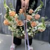 Large peach rose and white flower basket arrangement with long pastel ribbons