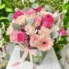 Pink and peach roses, carnations, and gerbera daisies in a glass cube vase with a pink ribbon bow