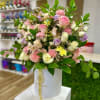 Pastel arrangement of roses, carnations, and mums in a white hat box-style container.