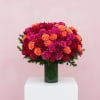 Bouquet of red, pink, and orange roses in a green glass vase