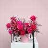 Pink roses and orchids in a pink hat box with black ribbon