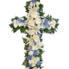 Cross-shaped floral arrangement with white lilies, roses, and blue hydrangeas