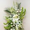Tall white floral arrangement with roses, orchids, and palm fronds