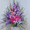 Tall arrangement of pink roses and purple flowers in a dark vase