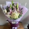 Bouquet of pink lilies and pale hydrangea wrapped in lavender paper