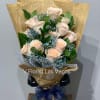 Bouquet of pale peach roses with blue filler flowers in newspaper-style wrap