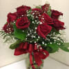 Arrangement of red roses and white filler flowers in a clear glass vase with a red bow