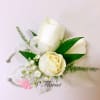 White rose wrist corsage with small white filler flowers and sheer ribbon on a silver cuff.