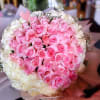 Large round bouquet of pink roses encircled by white roses in pastel wrapping paper