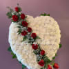 Heart-shaped white floral arrangement with red roses on a stand