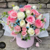 Pink and white rose arrangement in a round pink hatbox with blue filler flowers