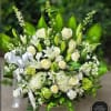 Large white and green sympathy basket with roses, lilies, hydrangeas, and a white ribbon bow.