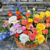Colorful mixed basket of roses and other blooms in pink, yellow, orange, and blue.