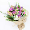 Bouquet of purple roses and mixed small flowers wrapped in kraft paper