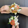 A Corsage and Boutonniere set in Peach and White. Topped off with