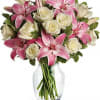 Pink lilies and white roses arranged in a clear glass vase