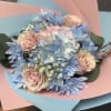 Bouquet of pale pink roses and blue flowers wrapped in pink and blue paper