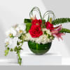 Red roses and white orchids in a green glass vase