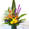 Tropical arrangement with yellow roses and orange bird-of-paradise in a glass vase