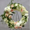 Floral wreath of white and peach roses on a black stand