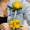 A vivid yellow rose wrist corsage paired with a matching boutonniere makes
