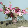Pink and white floral arrangement in a ceramic vase with three black candles