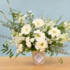 White gerbera daisies and mixed white flowers in a patterned vase