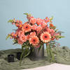 Peach and pink floral arrangement in a ribbed vase with candles nearby