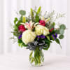 Bouquet of white hydrangeas, pink lilies, and roses in a glass vase