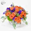 Orange roses with purple filler flowers in a square silver vase