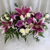 Pink lilies and purple roses arranged with small white flowers.