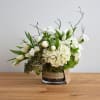 White floral arrangement in a glass vase with tulips and hydrangeas