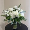 White roses and hydrangeas with eucalyptus in a clear glass vase on a round black table