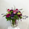 Pink roses and purple flowers in a clear glass vase