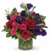 Bouquet of red, pink, and purple roses in a glass vase