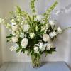 White floral arrangement in a clear glass vase with tall green spikes