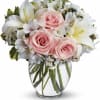 Pink roses and white lilies arranged in a clear glass vase