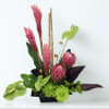 Pink tropical flowers arranged in a black container with green accents