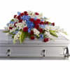 Red roses, white lilies, and blue flowers arranged on a silver casket